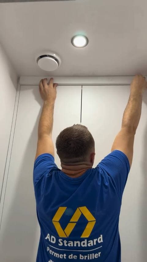 Plaatsen van de plafondlijst in een afgewerkte badkamer, naast de afzuiging en een inbouwspot